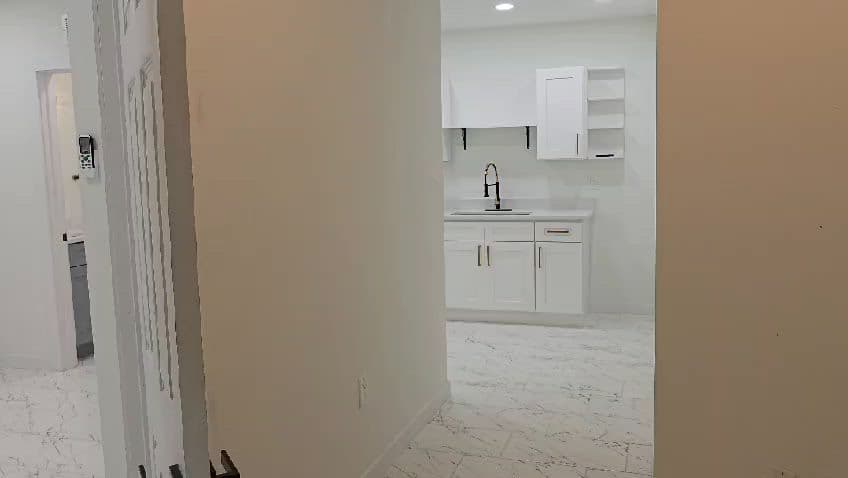 White kitchen cabinets, black faucet, and marble-look tile flooring