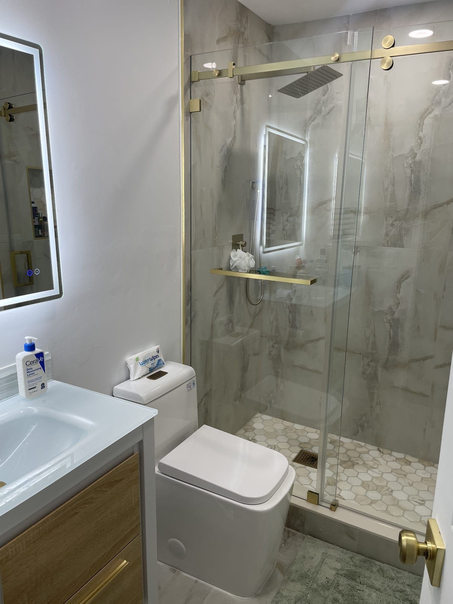Walk-in shower with marble tile, gold hardware, and a sliding glass door