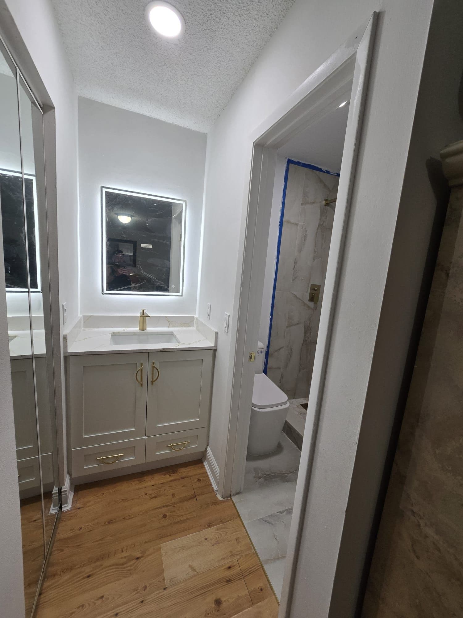 Bathroom hallway with a white vanity, quartz top, and gold faucet